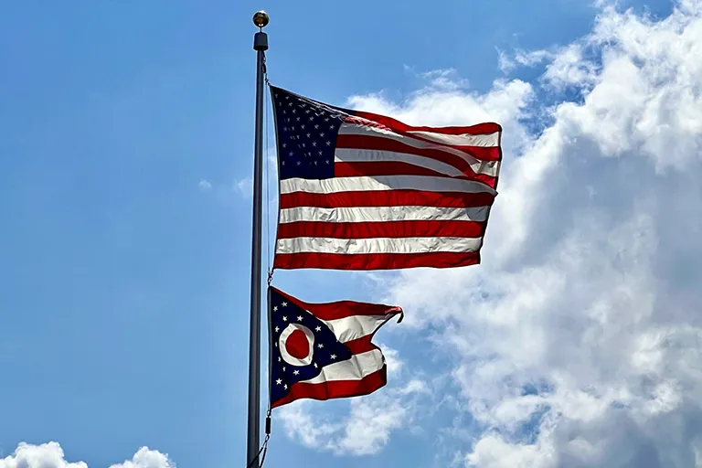 American and Ohio flags flying on a flag pole by a building that uses performance bonds for government projects in Napoleon