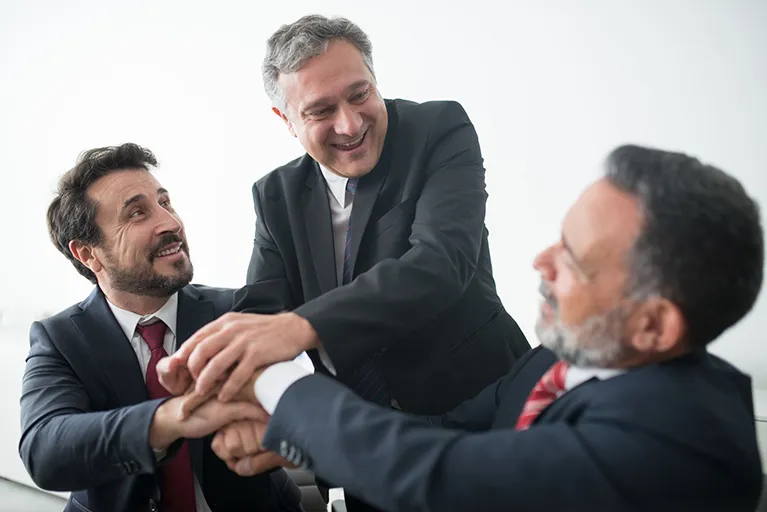 Three businessmen with their hands held together who just agreed to use commercial surety bonds in Maumee